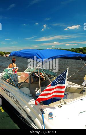 Une femme adulte tire son petit bateau dans un port de plaisance sur un lac au cours d'un bel après-midi chaud et ensoleillé en été Banque D'Images