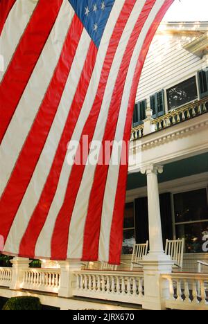 Un drapeau américain se balance dans la brise devant une maison patriotique le 4 juillet Banque D'Images