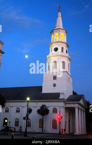 Une pleine lune s'élève dans le ciel crépuscule derrière un clocher illuminé de l'église St Michaels à Charleston, en Caroline du Sud Banque D'Images