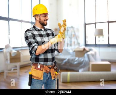 joyeux homme constructeur dans le casque et les gants à la maison Banque D'Images