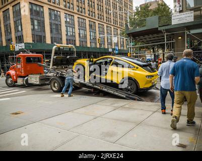 Un camion de remorquage se prépare à retirer un taxi Ford Mustang Mach-E EV désactivé à Chelsea, à New York, dimanche, 21 août 2022. En juillet, Ford a livré 4 970 Mustangs de véhicule électrique qui se vendent mieux que la Mustang à essence. (© Richard B. Levine) Banque D'Images