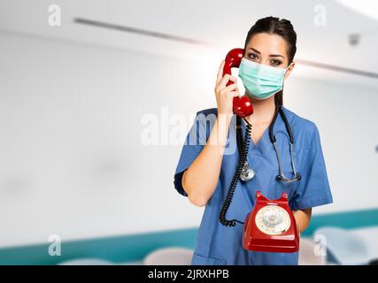 Infirmière faisant un appel téléphonique, avec un vieux téléphone covid et coronavirus concept Banque D'Images