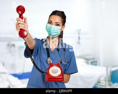 Jeune infirmière effectuant un appel téléphonique, avec un vieux concept de covid de téléphone et de coronavirus Banque D'Images