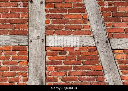 Texture de fond d'un vieux mur de cadre en bois, composé de poutres en bois altérées et de briques de pierre à bakestone rouges, typique pour l'architecture à colombages Banque D'Images