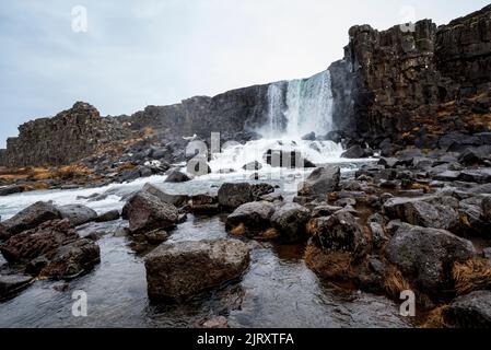 La belle cascade d'Öxarárfoss s'écoule de la rivière Öxará sur des rochers de basalte noir dans la gorge d'Almannagjá, parc national de Þingvellir, Islande Banque D'Images