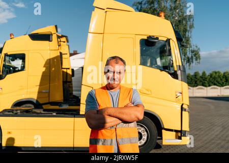 Portrait d'un homme mature caucasien sur un arrière-plan de stationnement de véhicules semi-routiers. Employé du conducteur de camion Banque D'Images