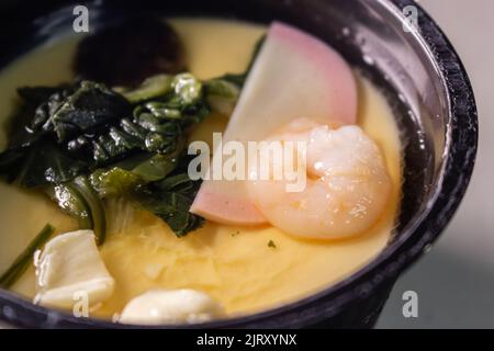 Gros plan sur le chawanmushi instantané. Le Chawanmushi est un plat japonais de crème anglaise aux œufs contenant des graines de ginkgo, du kamaboko, du Shiitake, des épinards, du poulet, etc Banque D'Images