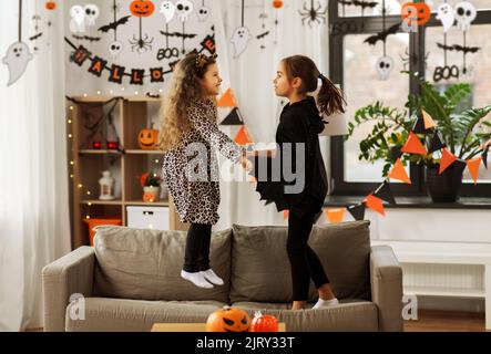 les filles en costumes d'halloween sautant sur le canapé Banque D'Images