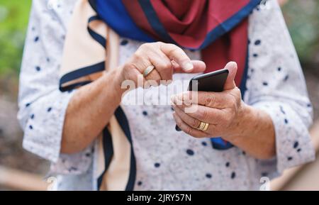 La vieille femme utilise son smartphone pour envoyer des SMS sur son téléphone mobile à l'extérieur Banque D'Images