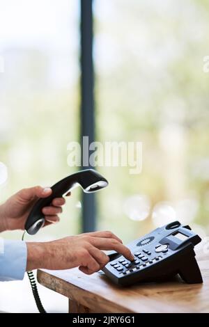 Ouverture des lignes de communication. Un homme qui compose un numéro sur un téléphone au travail. Banque D'Images