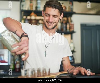 Verser avec précision. Un bon jeune barman verser des doses derrière le bar. Banque D'Images