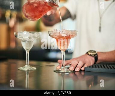 Froid glacé et délicieux. Un barman inidentifiable qui verse un cocktail derrière le bar. Banque D'Images