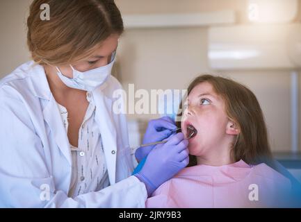 Un dentiste qui examine les dents d'une petite fille. Banque D'Images