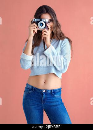 La vie est trop merveilleuse pour ne pas prendre de photos. Photo en studio d'une belle jeune femme posant avec un appareil photo vintage sur fond rose. Banque D'Images