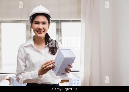 Femme d'ingénieur asiatique tenant un modèle de bâtiment, portrait d'un architecte professionnel intelligent jeune chef fille au bureau Banque D'Images