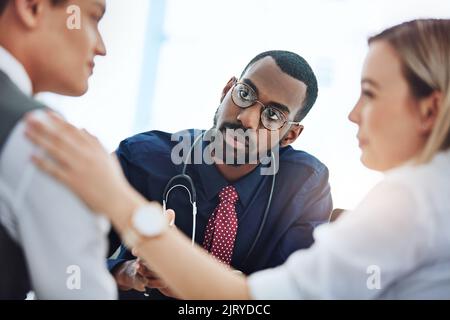 Ce n'est pas toutes de mauvaises nouvelles... un jeune couple ayant une consultation avec leur médecin. Banque D'Images