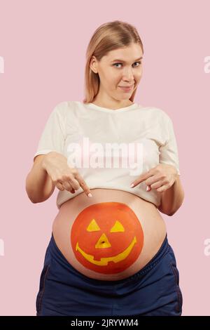 amusant jeune femme enceinte avec la citrouille halloween peint sur son ventre Banque D'Images
