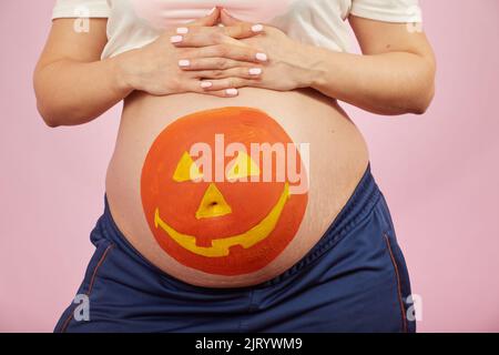 Jeune femme enceinte avec halloween citrouille peinte sur son estomac closeup portrait Banque D'Images