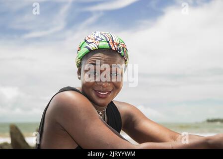 Bonne femme africaine avec headaddress du Ghana sur une plage sur la côte de l'Axim Ghana Afrique de l'Ouest Banque D'Images