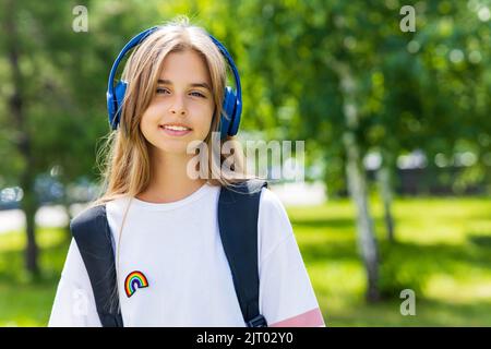 jeune fille d'âge avec sac à dos et casque dans le parc de retour à l'école concept Banque D'Images