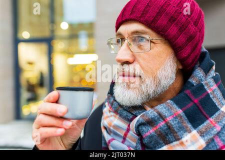 goog regardant l'homme mûr boire le thé chaud dans la rue de la ville en hiver Banque D'Images