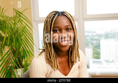 femme brésilienne avec des dreadlocks jaunes assis dans le salon Banque D'Images