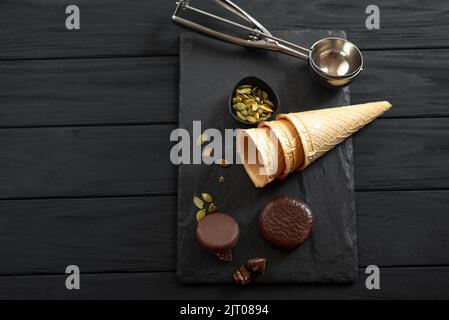 Le processus de fabrication de la crème glacée dans une tasse à gaufres. Vue de dessus. Ingrédients pour la glace sur fond de bois foncé Banque D'Images