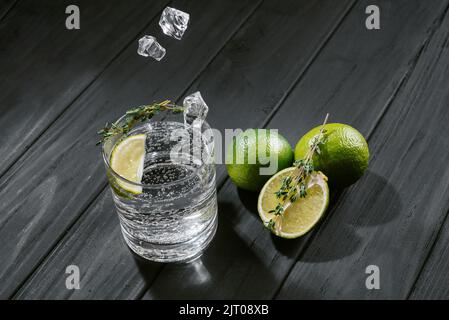 un séltzer dur à la chaux sur fond de bois foncé, des glaçons tombent dans un verre avec un séltzer dur à boisson alcoolisée Banque D'Images