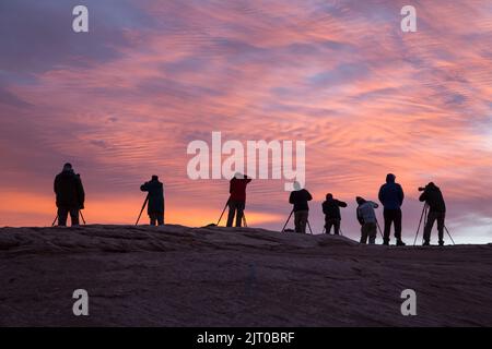 Silhouette d'un groupe de photographes dans un atelier photo prenant des photos au lever du soleil près de Moab, Utah. Banque D'Images