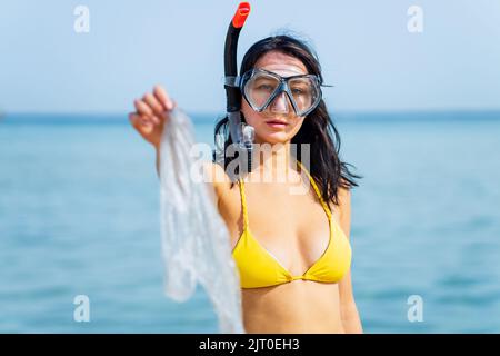 femme en bikini jaune et de la plongée ramasser une poubelle en plastique de la mer Banque D'Images