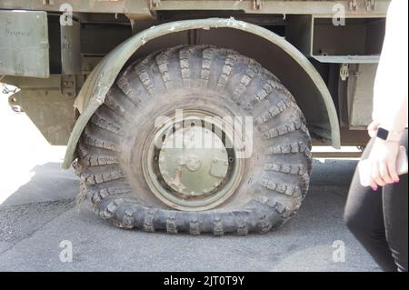 Pneu crevé et crevé d'équipement militaire du véhicule blindé. Le conflit militaire, le pilonnage de la roue. Gros plan. TI crevé Banque D'Images