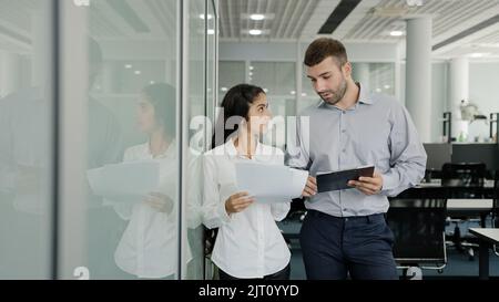 Les jeunes gens d'affaires, hommes et femmes collègues, se tiennent au bureau communiquer discuter du projet conjoint, fille stagiaire demande clarifie les détails de la tâche discussions avec le mentor Banque D'Images