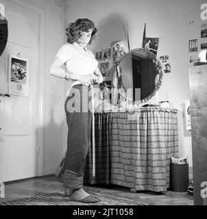 Dans le 1950s. Actrice Harriet Andersson née en 1932, photographiée chez elle lors de la mesure de sa taille. Elle porte un pantalon de jeans.Suède 1951 Conard réf. 1608 Banque D'Images