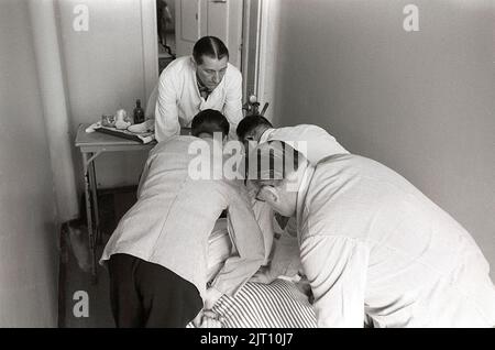 Dans le 1950s. Un intérieur d'un hôpital psychiatrique où un patient est vu allongé dans le lit étant retenu par quatre personnes. Les principes de la prise en charge des personnes ayant des problèmes psychologiques étaient très différents d'aujourd'hui. Les médicaments et les traitements étaient souvent expérimentaux. Suède 1953. Kristoffersson réf. 1A-39 Banque D'Images