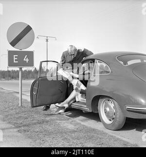 Couple dans le 1960s. Un jeune couple dans sa voiture de sport Porsche s'est arrêté le long de la route pour étudier la carte où aller. Suède 1962 Banque D'Images