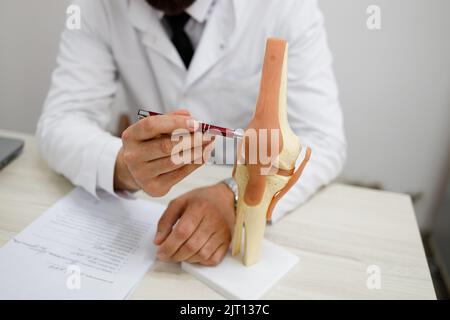 Vue rapprochée d'un médecin orthopédique qui démontre un modèle artificiel de l'articulation du genou Banque D'Images