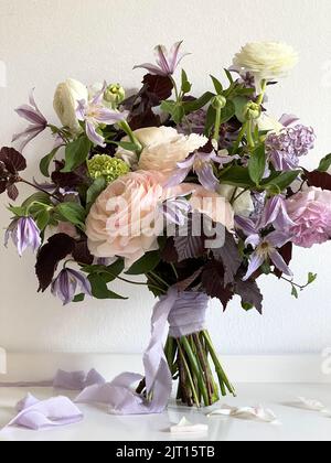 Bouquet de mariage avec un ruban violet se dresse contre le mur Banque D'Images