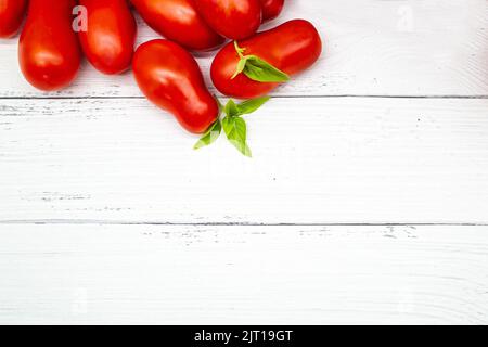 Vue de dessus des tomates fraîches et du basilic sur fond de bois blanc. Copier l'espace. Banque D'Images