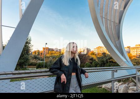 Belle fille blonde penchée dans un parc dans l'après-midi. Il y a un ciel bleu derrière elle Banque D'Images