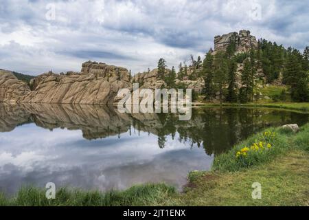 Les nuages de tempête d'été menacent d'effacer un reflet parfait des rives en granit du lac Sylvan dans les Black Hills du Dakota du Sud Banque D'Images