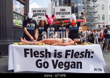 Londres, Royaume-Uni. 27th août 2022. Les militants du PETA (People for the Ethical Treatment of Animals) portant des masques pour animaux 'Dine' sur un activiste couvert de faux sang lors de la manifestation à Leicester Square. L'action, marquant la Journée mondiale pour la fin du spéciéisme, fait partie de la campagne en cours du PETA pour mettre fin au spéciéisme et encourager les gens à aller végétalien. Crédit : SOPA Images Limited/Alamy Live News Banque D'Images