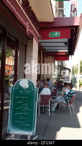 Vue sur la rue, Champagne au Mont d'Or, Rhône, Rhône Alpes, France. Les gens assis dans un café, boire et manger, bavarder. Banque D'Images