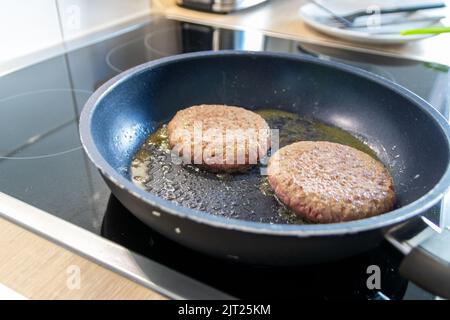 Deux patties hamburger hamburger viande qui se mêle dans une poêle chaude avec de la graisse et de l'huile comme délicieux hamburger barbecue boulettes de viande comme un repas rapide malsain déjeuner Banque D'Images