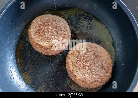 Deux patties hamburger hamburger viande qui se mêle dans une poêle chaude avec de la graisse et de l'huile comme délicieux hamburger barbecue boulettes de viande comme un repas rapide malsain déjeuner Banque D'Images