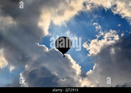 Telford, Shropshire, Royaume-Uni. 27 août 2022. Festival de montgolfière. Ballon d'air chaud silhoueted contre un ciel dramatique après avoir pris le départ de Telford Town Park.Credit: Dave Bagnall /Alamy Live News Banque D'Images