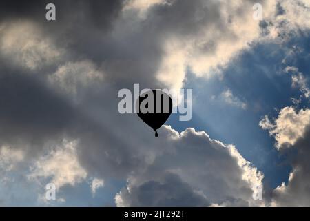 Telford, Shropshire, Royaume-Uni. 27 août 2022. Festival de montgolfière. Ballon d'air chaud silhoueted contre un ciel dramatique après avoir pris le départ de Telford Town Park.Credit: Dave Bagnall /Alamy Live News Banque D'Images