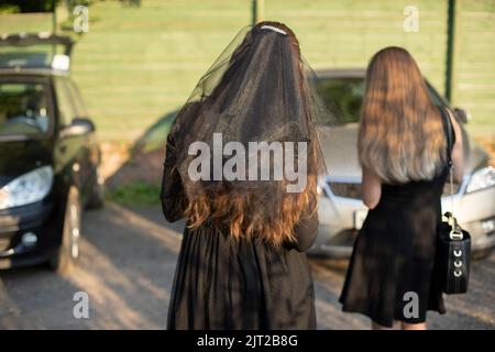 Filles dans le parking. Filles en robes noires. Détails de la cérémonie. Vêtements noirs. Banque D'Images