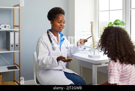 Le médecin informe la jeune fille de la courbure de la colonne vertébrale et de la prévention des problèmes de dos et de squelette. Banque D'Images