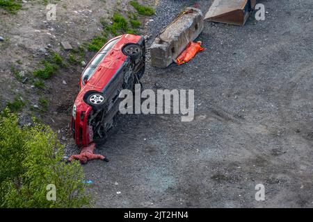 Göteborg, Suède - 02 juin 2022 : voiture rouge à ses côtés dans un centre d'entraînement de secours avec des mannequins d'entraînement dispersés. Banque D'Images