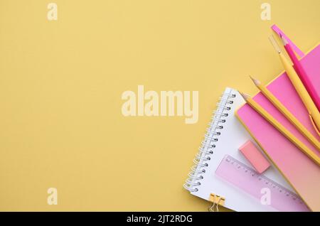 Fournitures de papeterie pour l'école sur fond jaune rose, platte. Retour à l'école Banque D'Images